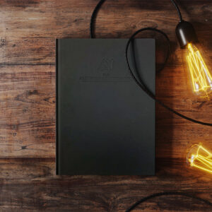 Prototype of ATAP beautiful black planner with with lit bulbs lying around it.